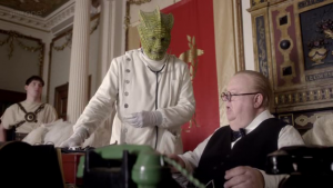 A Silurian talks to an actor who looks entirely unlike Winston Churchill, while behind him a Roman centurion stands